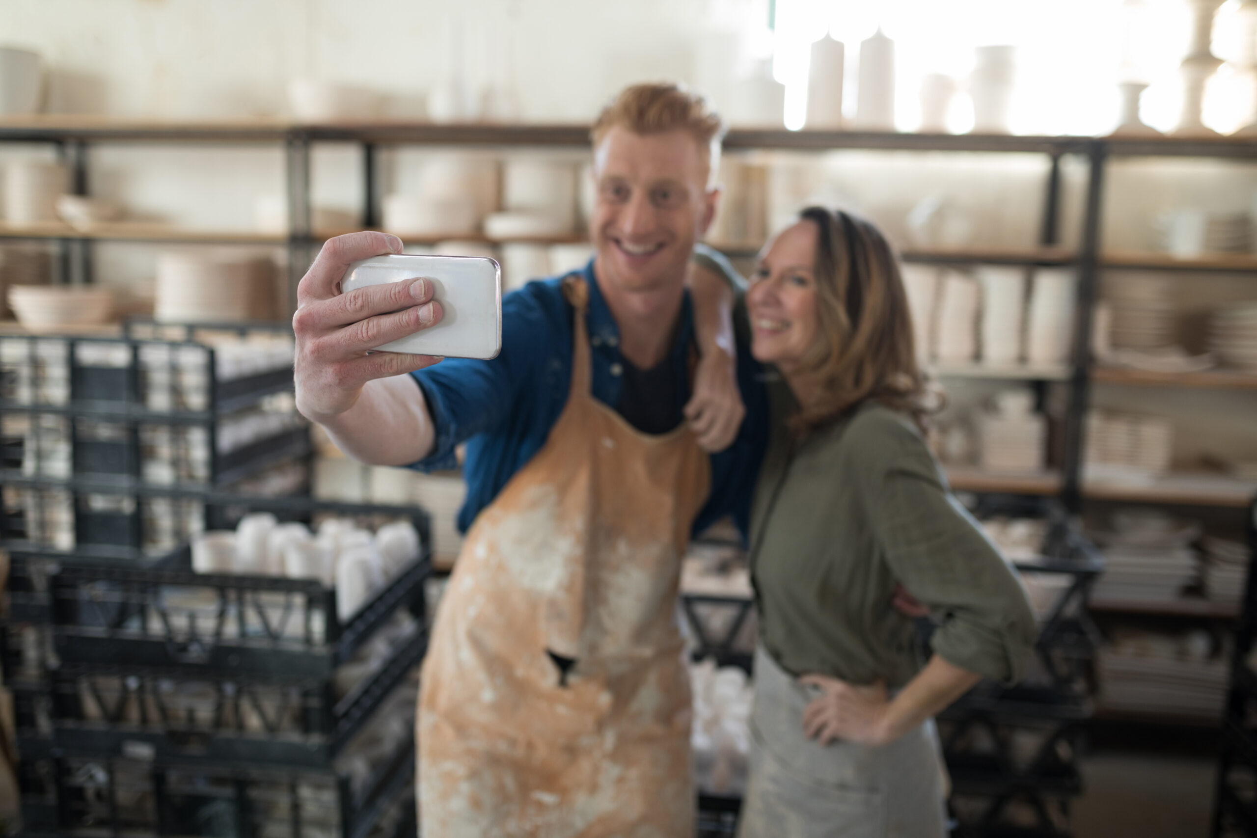 Male and female potter taking selfie with mobile phone